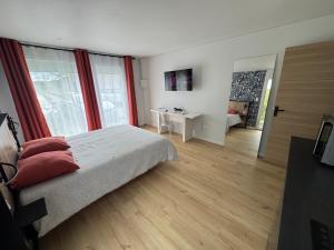a bedroom with a bed with red curtains and a desk at Studio La Salamandre in Plauzat