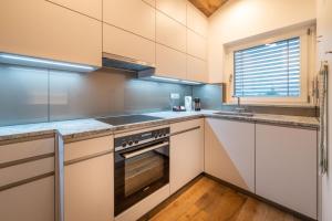 a kitchen with white cabinets and a stove at central sky-penthouse with iconic matterhorn view in Zermatt