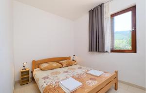 a white bedroom with a bed and a window at 1 Bedroom Stunning Apartment In Artatore in Cunski