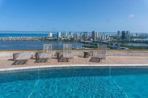 a group of chairs sitting next to a swimming pool at Vista mar - Flat Parque do Cais 1211 in Recife