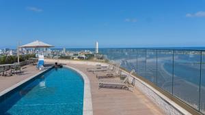 a swimming pool on top of a building next to the ocean at Vista mar - Flat Parque do Cais 1211 in Recife