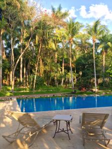 twee stoelen en een tafel naast een zwembad bij Hacienda Chichen Resort and Yaxkin Spa in Chichén-Itzá