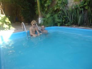 a man and a child sitting in a swimming pool at Beachhotel Morro do Careca in Natal