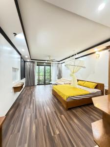 a bedroom with a yellow bed and wooden floors at Đầm sen Resort in Hòa Lạc +60 photos