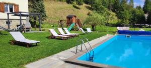 une piscine avec des chaises longues et une aire de jeux dans l'établissement 2chałupy - apartamenty w Soli, à Sól