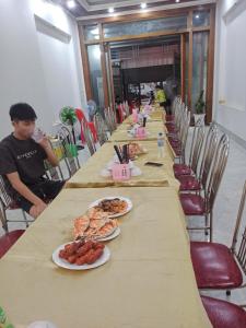 Una fila de mesas largas con platos de comida sobre ellas. en Nhà nghỉ Bình Liên, en Sầm Sơn