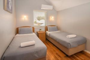two beds in a small bedroom with a window at Beachside Retreat, WIFI, Kayaks, AC to all rooms in Dunsborough