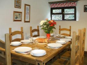 a wooden table with white plates and flowers on it at Cider House in Hawkchurch
