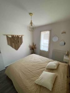 a bedroom with a large bed with two pillows at Appartement cosy avec Clim et jardin centre de Gujan in Gujan-Mestras