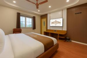 a bedroom with a bed and a desk and a television at Hotel Royale Heritage in Ujjain