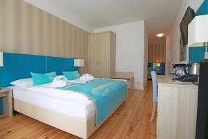 a bedroom with a bed with a blue headboard and a desk at Hotel Villa WellenRausch in Travemünde