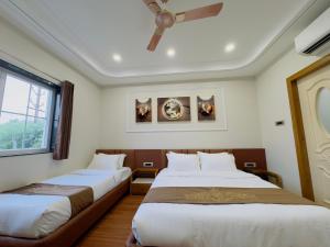 a bedroom with two beds and a ceiling fan at Hotel Royale Heritage in Ujjain