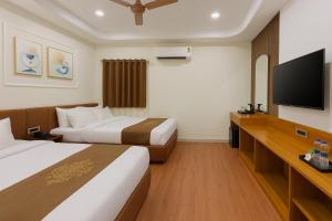 a hotel room with two beds and a flat screen tv at Hotel Royale Heritage in Ujjain