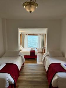 a bedroom with three beds and a large window at Hostería Nórdico Lake in San Carlos de Bariloche