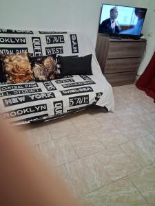 a bed with black and white comforter and a tv at Studio plage in Santa-Maria-di-Lota