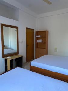 a bedroom with two beds and a mirror and a door at Eesan Guest House in Trincomalee