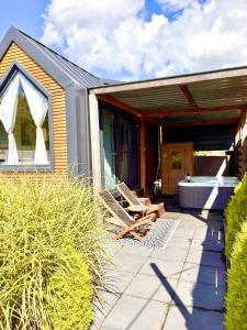 une maison avec une baignoire posée sur un patio dans l'établissement Tiny house with sauna & jacuzzi near Amsterdam, à Vijfhuizen