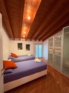 Dos camas en una habitación con techos de madera. en La Meridiana, en Lonato