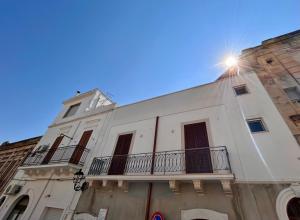 un edificio bianco con un balcone e il sole che splende su di esso di La casetta della piazza a Carovigno