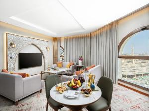 a living room with a table and chairs and a television at Elaf Taiba Hotel in Medina