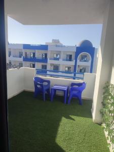 a balcony with blue chairs and a table and a building at Luxuries Studios and apartments in Oasis Marina ,Hurghada in Hurghada