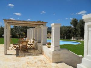 un patio con mesa y sillas junto a una piscina en B&B Lamascopone, en Fasano