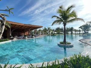 a large swimming pool with a palm tree in the middle at voco Quang Binh Resort by IHG in Dong Hoi