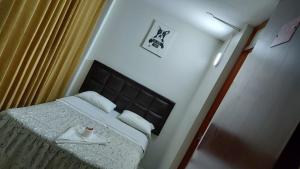 a small bedroom with a bed with a black headboard at Hostal Yulys in Lima