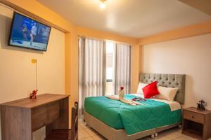 Un dormitorio con una cama con un televisor en la pared. en VILLA andina cusco, en Cusco