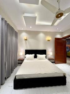 1 dormitorio con 1 cama grande con 2 lámparas y cortinas en The Grand Haven - 3BHK, en Islamabad