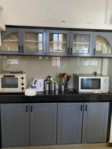 a kitchen with blue cabinets and microwaves at Eesan Guest House in Trincomalee