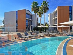 a swimming pool with chairs and umbrellas next to a building at SoBlue Hôtel in Antibes