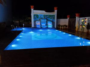 a swimming pool at night with blue lights at Rajbari Resort in Shānti Niketan +10 photos
