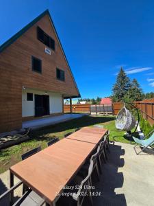 a wooden table and chairs in front of a building at Vila ALDIMARA in Žabljak