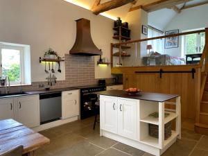 a kitchen with white cabinets and a black counter top at Private & Spacious Cotswold Barn in Hankerton