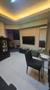 a living room with a tv and a chair and a table at Apt conforto e aconchegante prox a Novafapi e ao Shopping Carnauba in Teresina