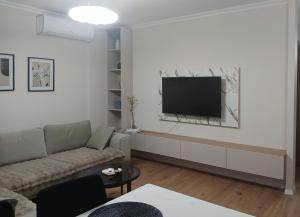 a living room with a couch and a flat screen tv at Magnolia's Apartment in Yzberishti +18 photos
