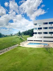 a building with a swimming pool next to a grass field at (103) Beach Garden na praia da litorânea in Pimenta