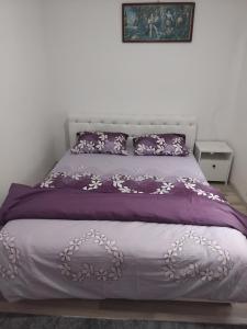 a bed with a purple comforter and pillows at Apartmani Nurka in Orašac
