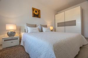a bedroom with a large white bed with two lamps at Apartments Villa Residenca in Novi Vinodolski