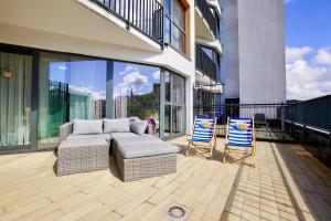 a patio with a couch and two chairs on a balcony at Horyzont by Baltic Home in Międzyzdroje