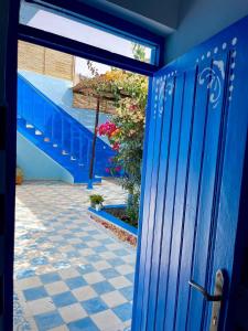 a blue door leading to a courtyard with flowers at The blue house in Taghazout