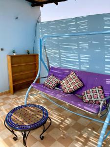 a purple bench with three pillows and a table at The blue house in Taghazout