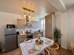 a kitchen with a table with a bowl of fruit on it at Les Cocons d'Agathe, La Marinière, la plage à pieds in Larmor-Plage +31 photos