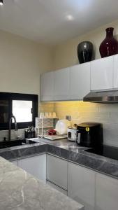 une cuisine avec des armoires blanches et un comptoir dans l'établissement ZMZ Silang Transient House near Tagaytay, à Silang