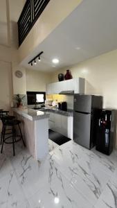 une cuisine avec un sol en marbre blanc et un réfrigérateur noir dans l'établissement ZMZ Silang Transient House near Tagaytay, à Silang