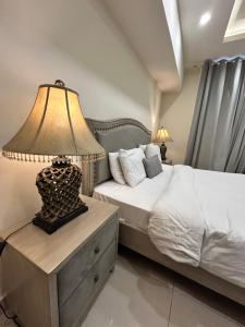 a bedroom with a bed with a lamp on a night stand at Elysium Serviced Apartments By LMY Blue Area Facing Centaurus Mall Islamabad in Islamabad