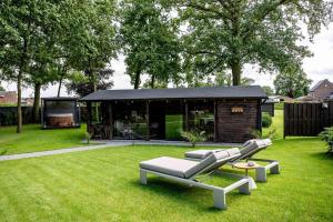 布雷Maison Idyllique的一栋黑色屋顶的房子,草地上有一张长椅