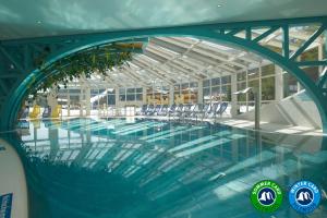 a large swimming pool with chairs in a building at Die Filzmooserin - smart living apartments in Ski amadé, Filzmoos Card inklusive in Filzmoos +101 photos