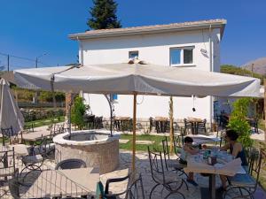 a woman and child sitting at tables under an umbrella at Villa Aurea Rooms & More in Papasidero